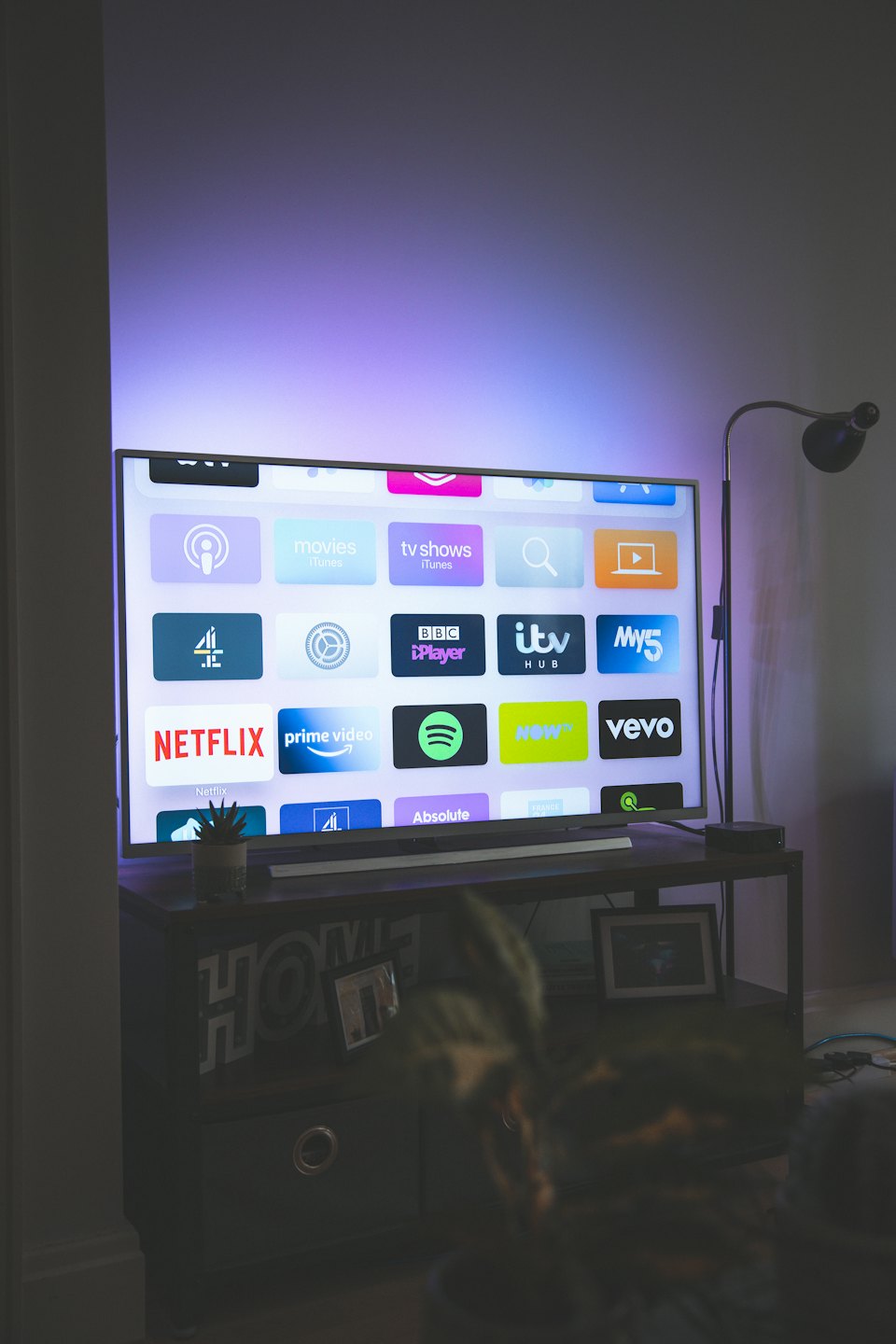 Television screen showing streaming apps with purple backlight.