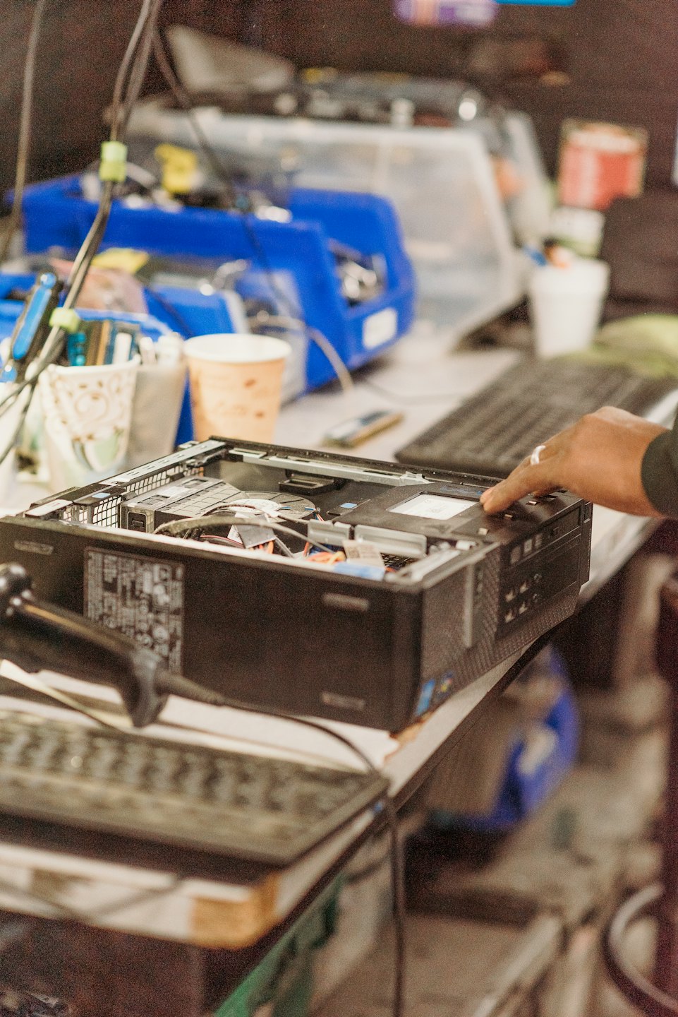 Hand reaches into open desktop computer case for repair.