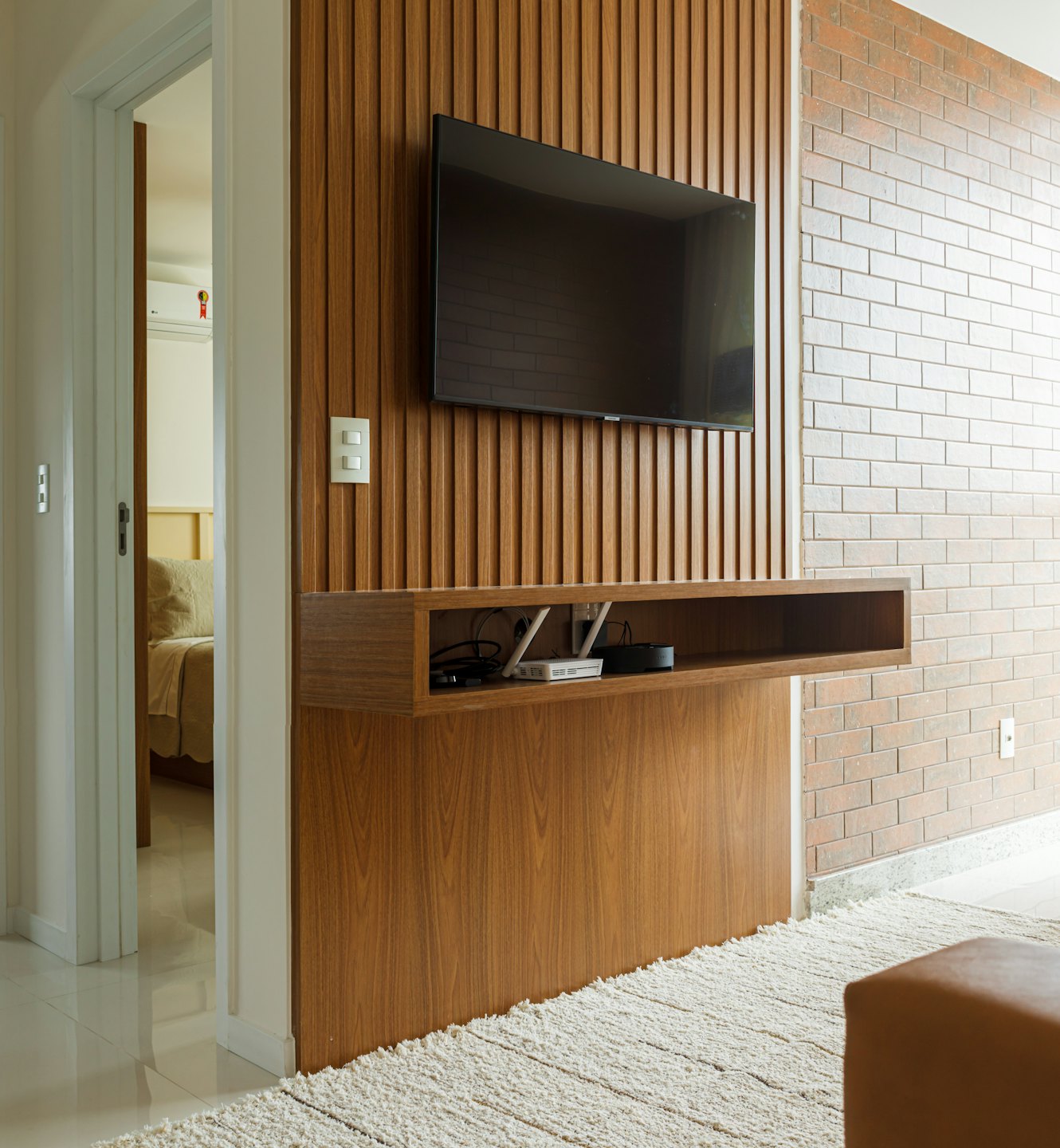 Modern living room with TV and media console on wood wall.